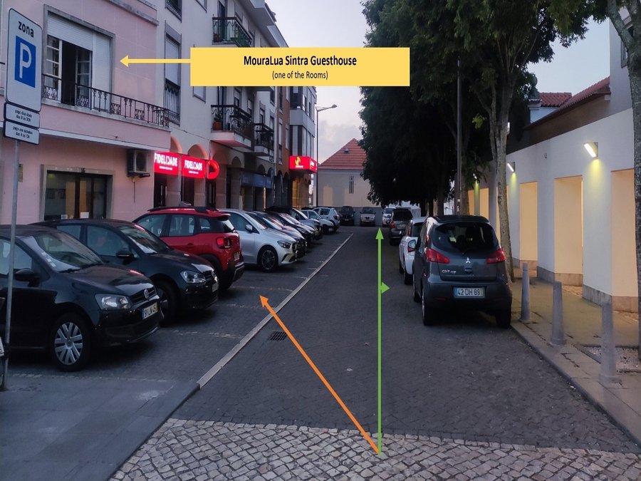 Rua junto à MouraLua com indicação do parque público pago (seta laranja) e da zona gratuita (setas verdes)